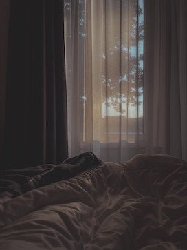 10 konkrete Ratschläge gegen Herzschmerz: Frau in Bett, abgedunkelter Raum